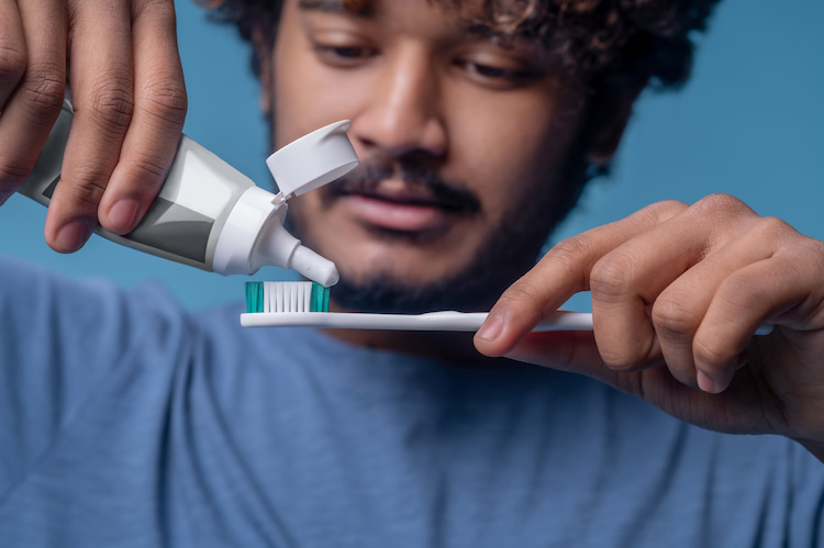 a man using gentle toothpaste after teeth whitening.