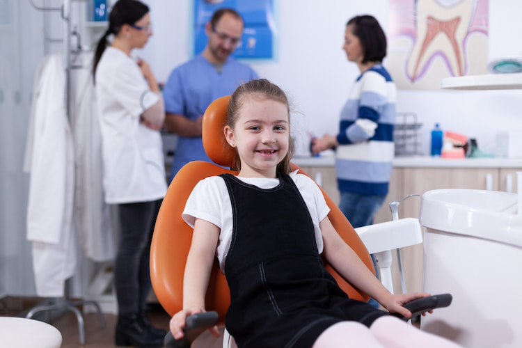 a child is sitting on a dental chair and her mother is talking to dentists about CDCP for Kids Scarborough.