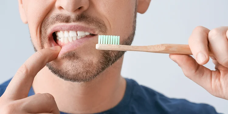 A picture of a man brushing his teeth with manual toothbrush