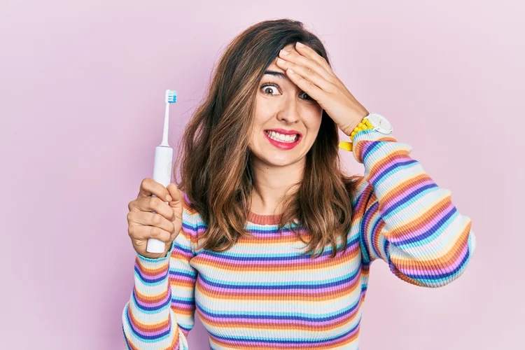 A picture of a lady with an electric toothbrush
